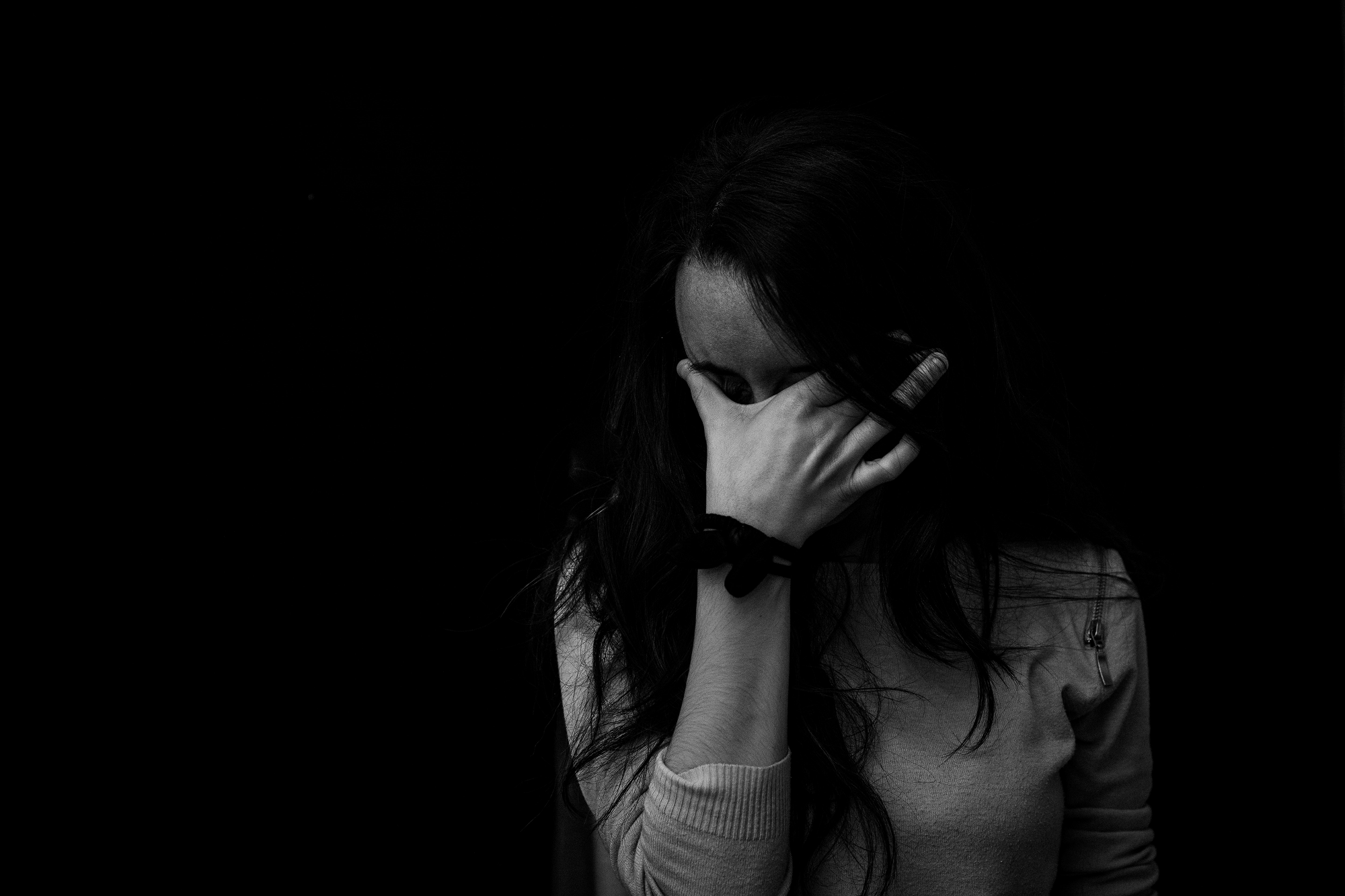 A black and white image of a woman with her hand covering her face